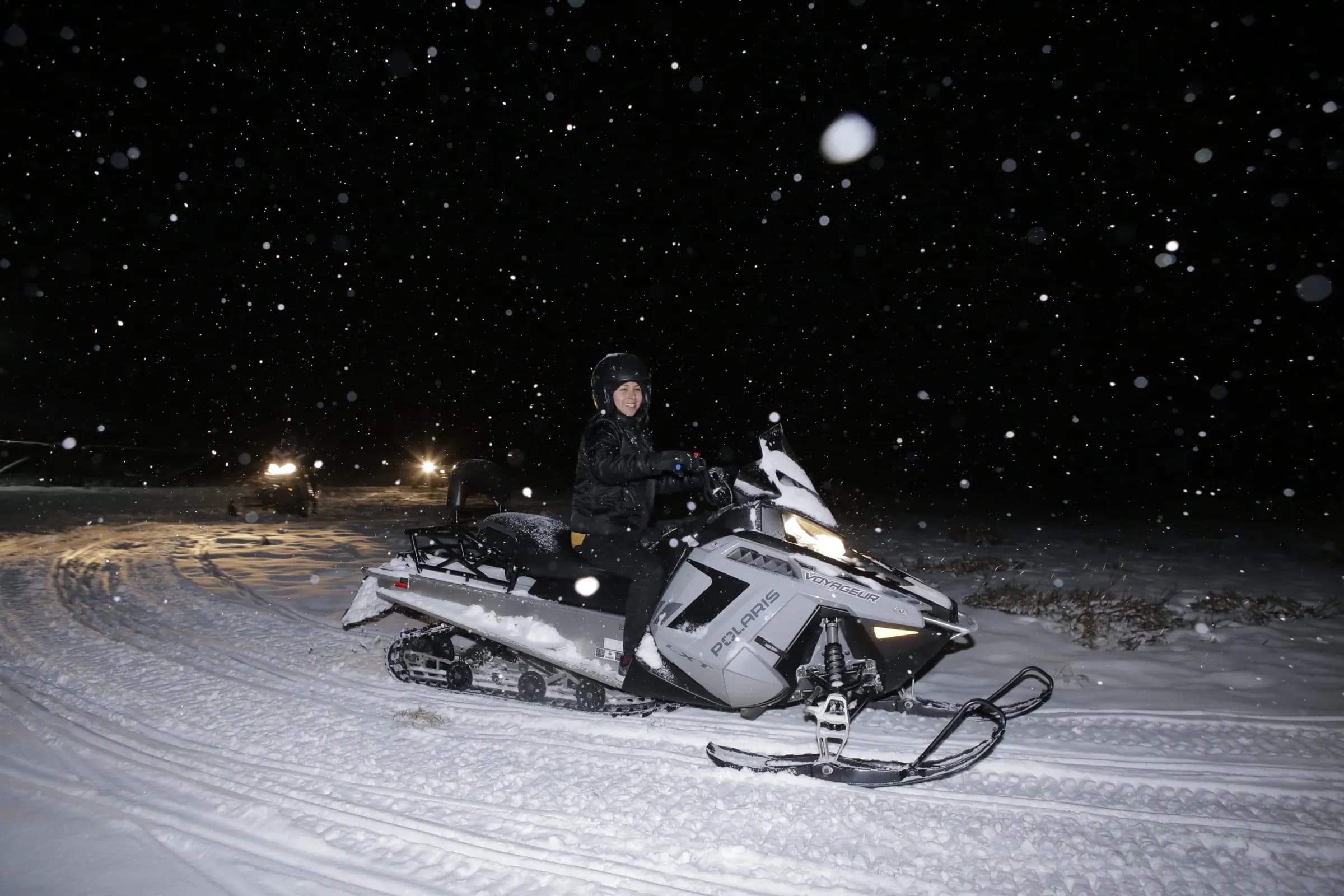 Paseo en moto de nieve Polaris bajo la nevada nocturna en Llanos del Castor